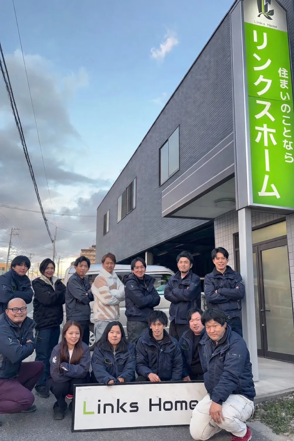 リンクスホームの看板の前に並ぶ社員